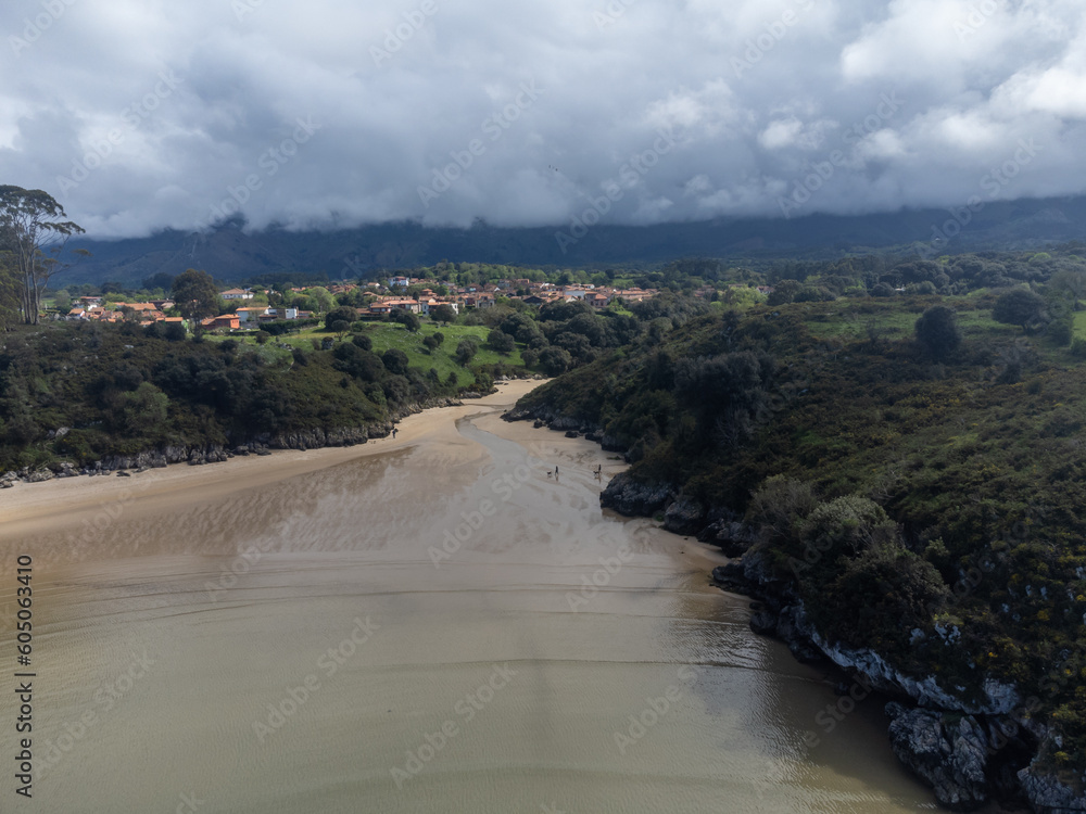 Aerial view on Playa de Poo during low tide near Llanes, Green coast of Asturias, North Spain with sandy beaches, cliffs, hidden caves, green fields and mountains. Aerial view on Playa de Poo during low tide near Llanes, Green coast of Asturias, North Spain with sandy beaches, cliffs, hidden caves, green fields and mountains.