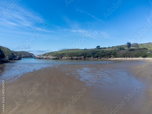 Aerial view on Playa de Poo during low tide near Llanes  Green coast of Asturias  North Spain with sandy beaches  cliffs  hidden caves  green fields and mountains.