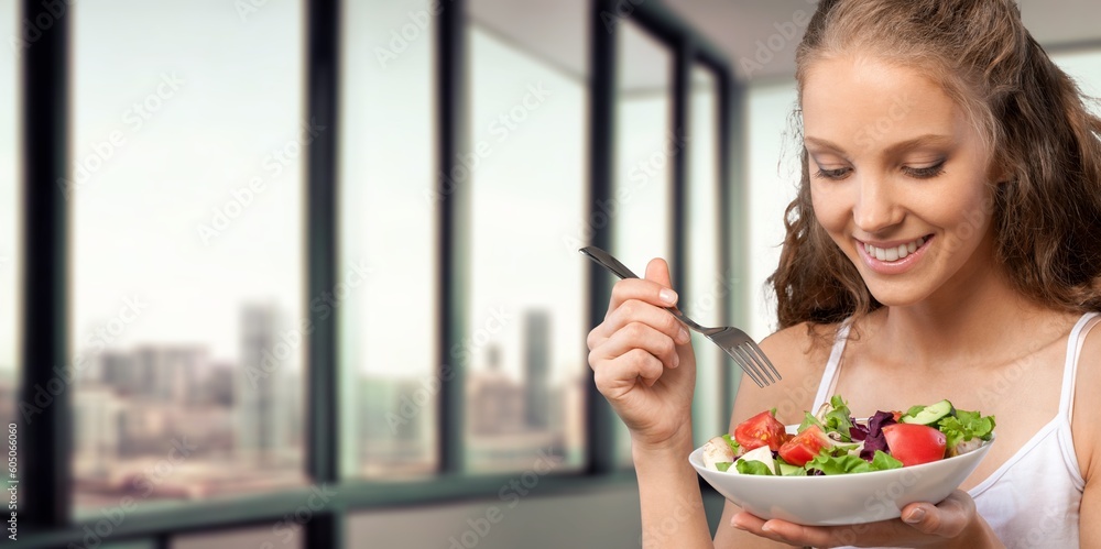 Happy young woman eat salad at home