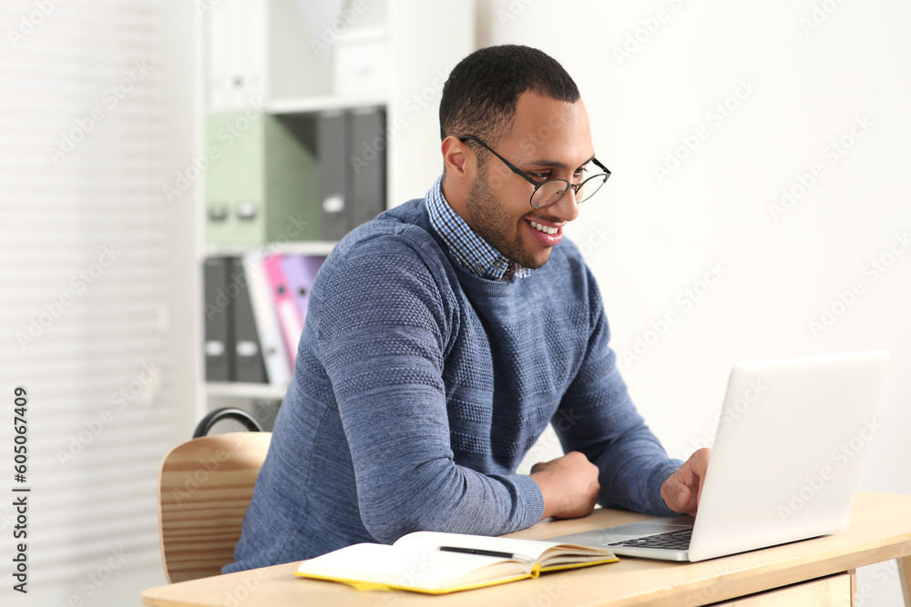 African American man in glasses working on laptop indoors African American man in glasses working on laptop indoors