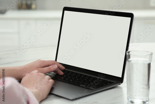 Woman using laptop at white table indoors, closeup