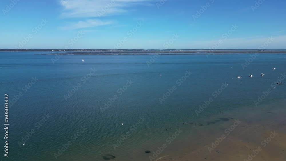 People walk exercising in shallow sandy waters with wetsuits at Arcachon Bay France, Pan left shot People walk exercising in shallow sandy waters with wetsuits at Arcachon Bay France, Pan left shot