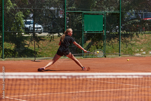 A young girl showing professional tennis skills in a competitive match on a sunny day, surrounded by the modern aesthetics of a tennis court. © .shock