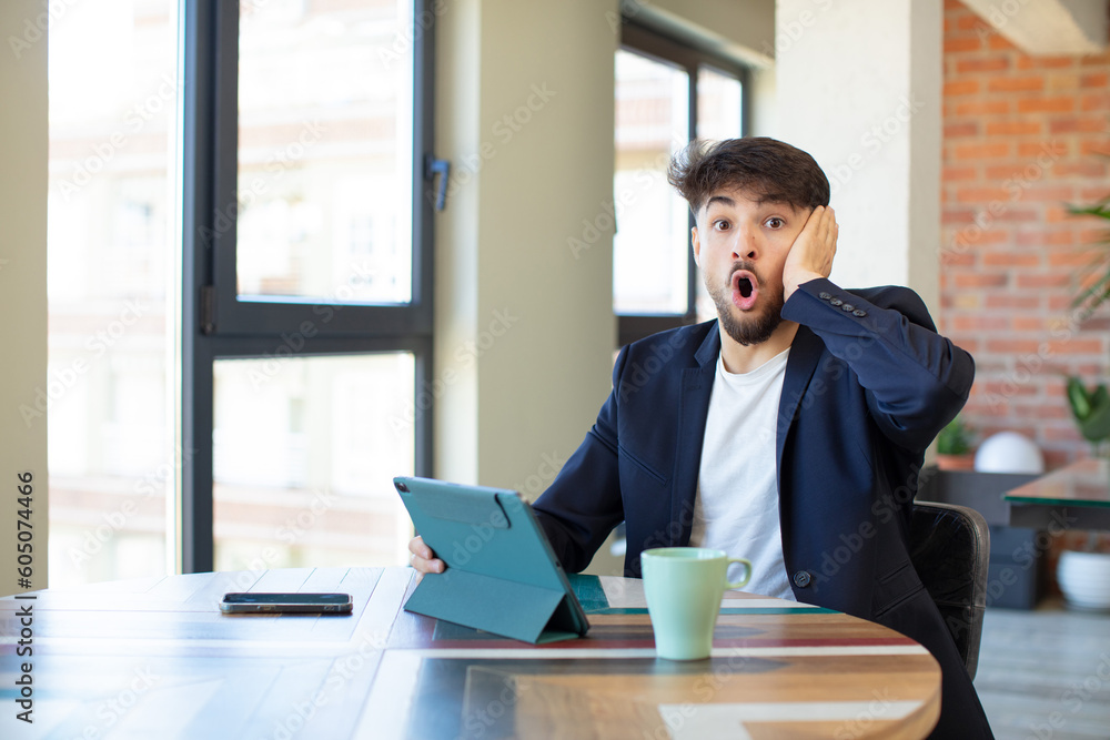 young handsome man feeling extremely shocked and surprised. touch screen pad concept young handsome man feeling extremely shocked and surprised. touch screen pad concept
