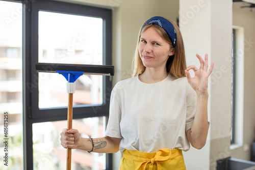 young pretty woman feeling happy, showing approval with okay gesture. windows washer concept