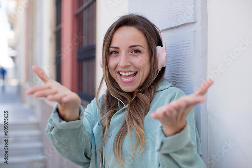 pretty woman smiling happily and offering or showing a concept. headphones and music concept