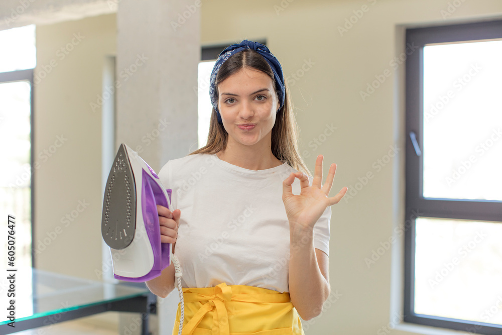 young pretty woman feeling happy, showing approval with okay gesture. housekeeper and laundry concept young pretty woman feeling happy, showing approval with okay gesture. housekeeper and laundry concept