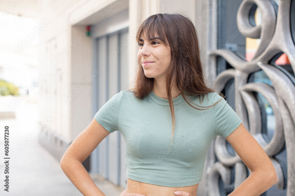 pretty young woman looking happy, cheerful and confident, smiling proudly and looking to side with both hands on hips pretty young woman looking happy, cheerful and confident, smiling proudly and looking to side with both hands on hips