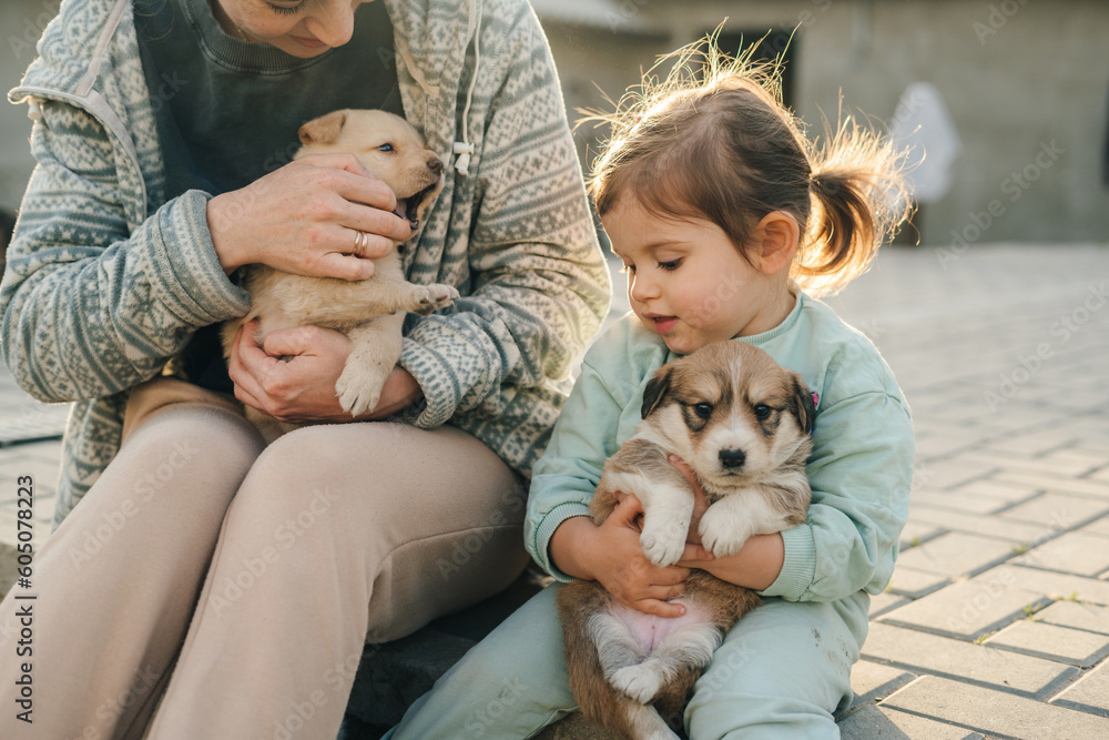 Happy family of mother and daughter relaxing and sharing moment of love petting the puppies outdoors, trust and care. Mother nature. Cute animal. Happy family of mother and daughter relaxing and sharing moment of love petting the puppies outdoors, trust and care. Mother nature. Cute animal.