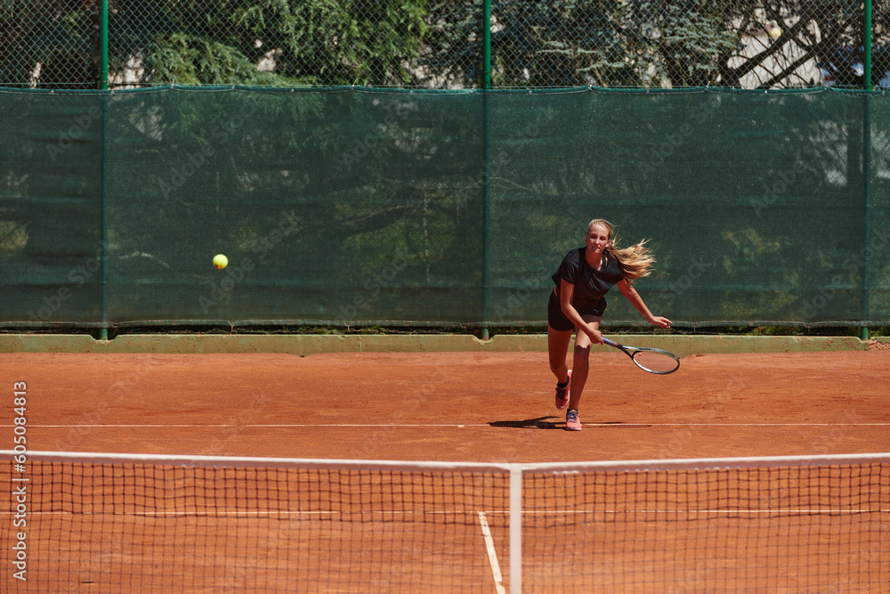 A young girl showing professional tennis skills in a competitive match on a sunny day, surrounded by the modern aesthetics of a tennis court.