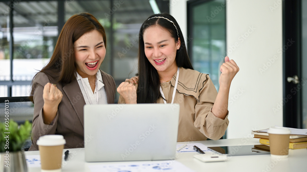 Two excited Asian businesswomen showing clenched fists, rejoicing and celebrating Two excited Asian businesswomen showing clenched fists, rejoicing and celebrating