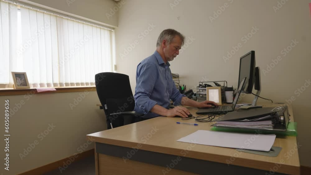 Sitting businessman in an office typing on his laptop, locked off Sitting businessman in an office typing on his laptop, locked off