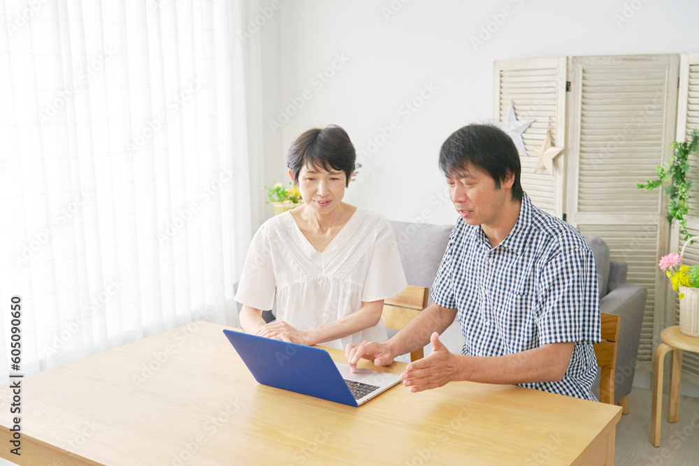 リビングでノートパソコンを見る熟年夫婦