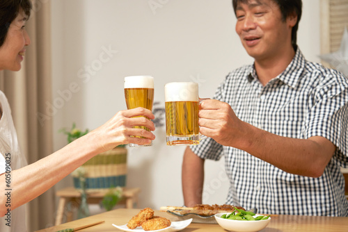 自宅でビールで乾杯をする熟年夫婦