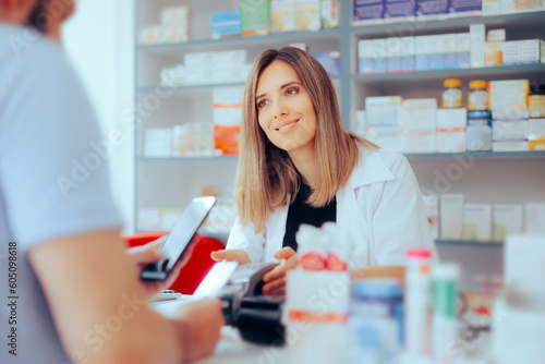 Customer Paying at the Pharmacy using Credit Card Method of Payment. Happy pharmacist assisting a patient to make pharmaceutical purchase 
