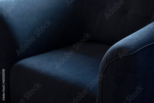 Upholstered furniture made of velor blue fabric with rounded elbows close-up. An element of upholstered furniture with a stitched sidewall in deep shadows with an empty space for text with copy space.