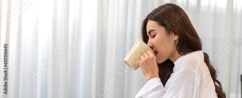 Portrait of smiling happy enjoy beauty asian woman relax drinking cup of hot coffee or tea,Cappuccino,Espresso,Americano,Latte.Girl felling enjoy breakfast in holiday morning vacation on bed at home