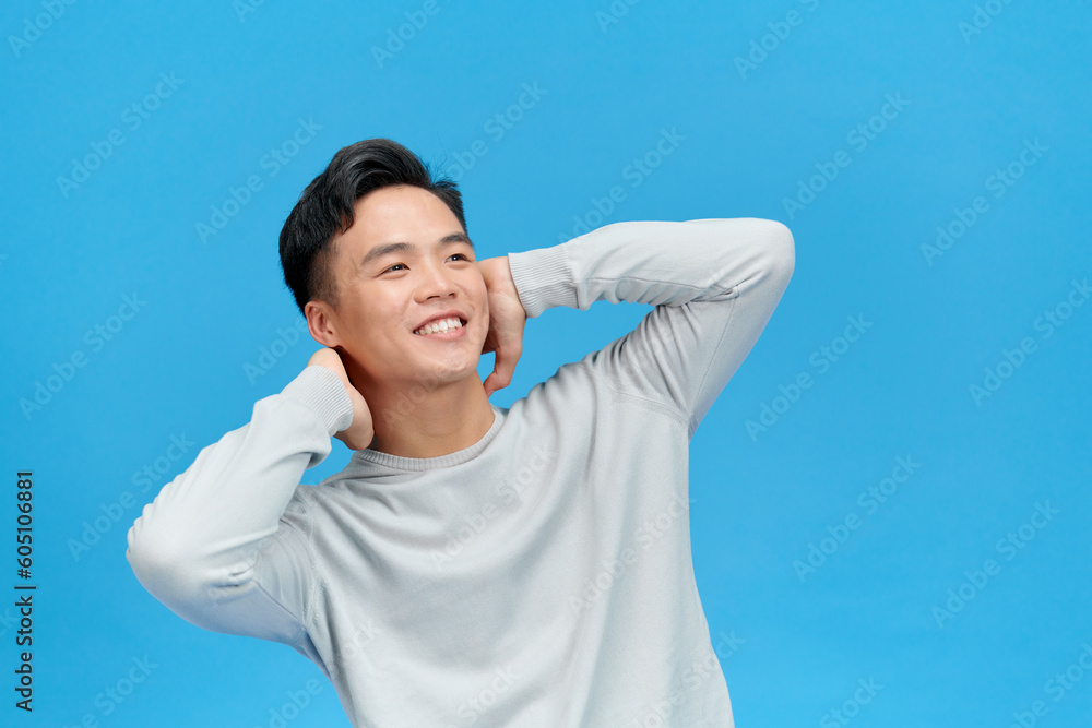 Naklejka premium Young relaxed happy handsome man folded hands behind head posing isolated on over blue background
