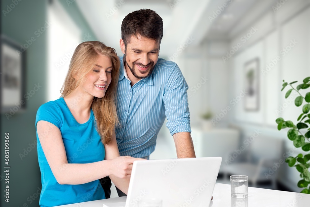 Two cheerful office workers work with laptop,