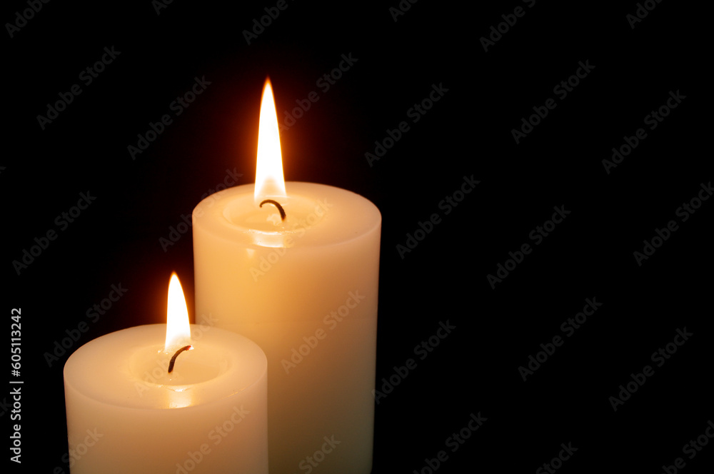 Two burning candles on black background with space for text. Two burning candles on black background with space for text.