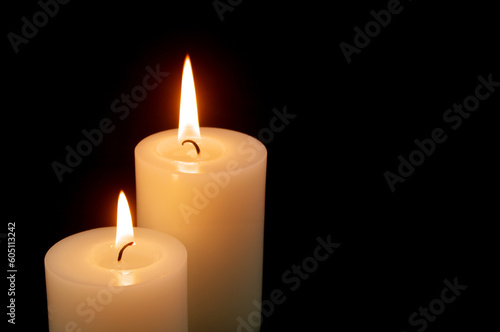 Two burning candles on black background with space for text.