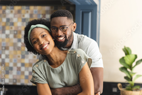 Portrait of happy african american couple embracing and smiling in kitchen
