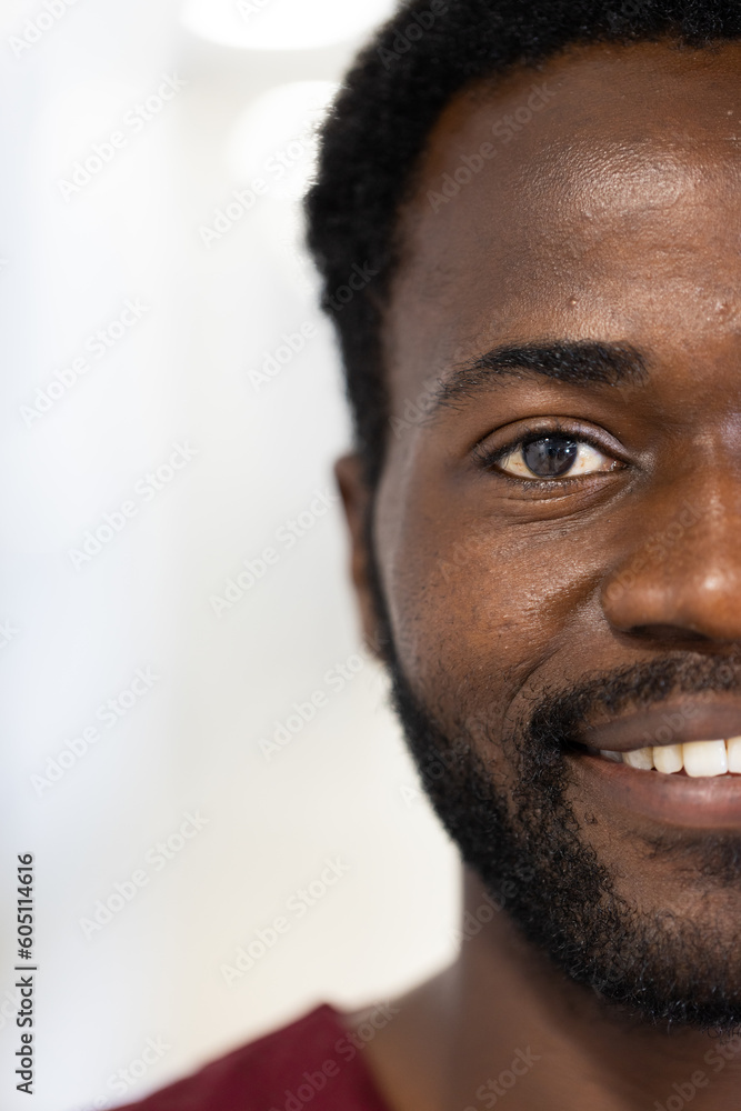 Obraz premium Unaltered portrait of half face of happy african american male doctor smiling, with copy space