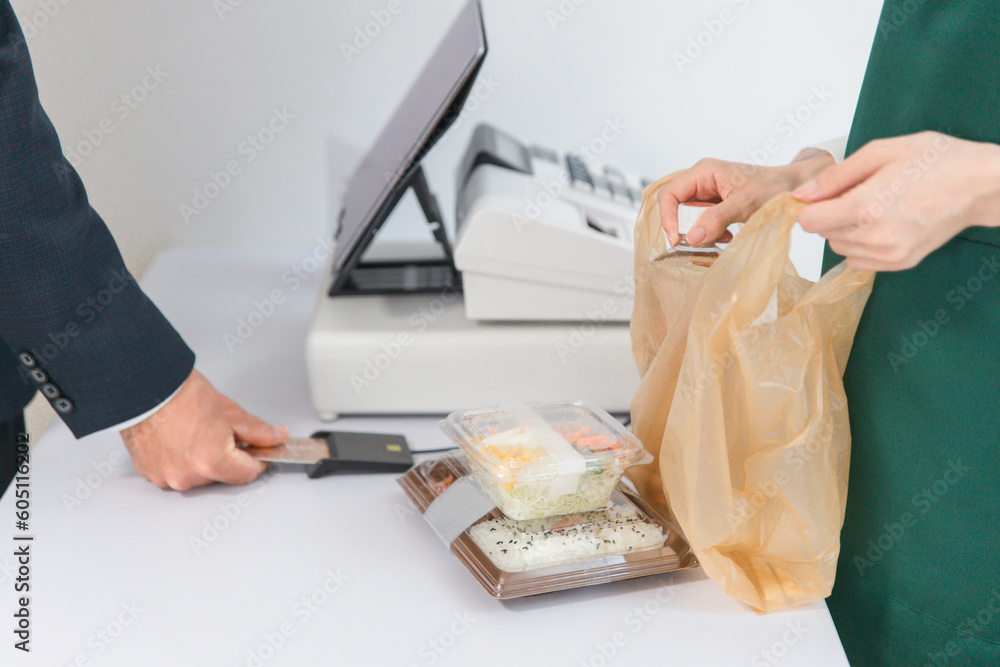 © buritora - コンビニ・スーパーでクレジットカードを使ってキャッシュレス決済するビジネスマン