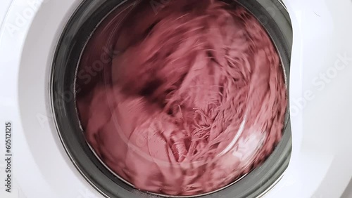 The rotation of a pink fluffy plaid in a white washing machine. Cleaning and tidying up the house.