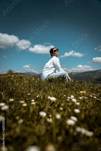 Stylish woman in a white shirt and glasses posing against the backdrop of mountains