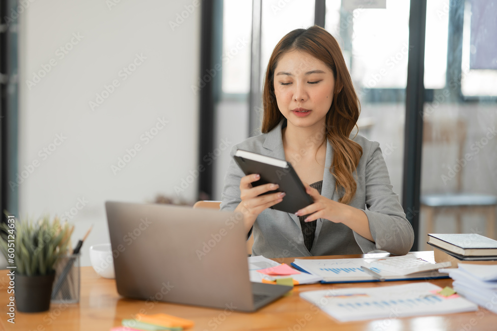 Asian businesswoman holding notebook about business, spending money Asian businesswoman holding notebook about business, spending money