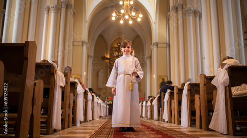 boy before first communion in a catholic church. child in white clothes with a candle in the church