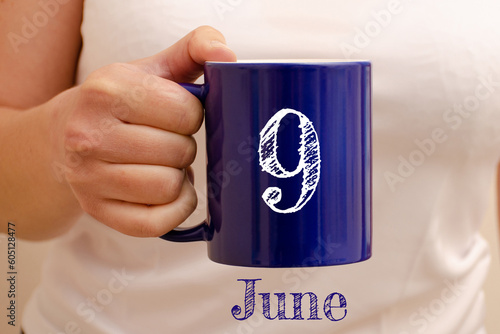 The inscription on the blue cup 9 june. Cup in female hand, business concept