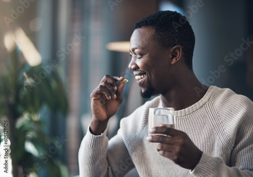 Foto Black man, pill or medicine and a glass of water in a house for health and wellness with a smile
