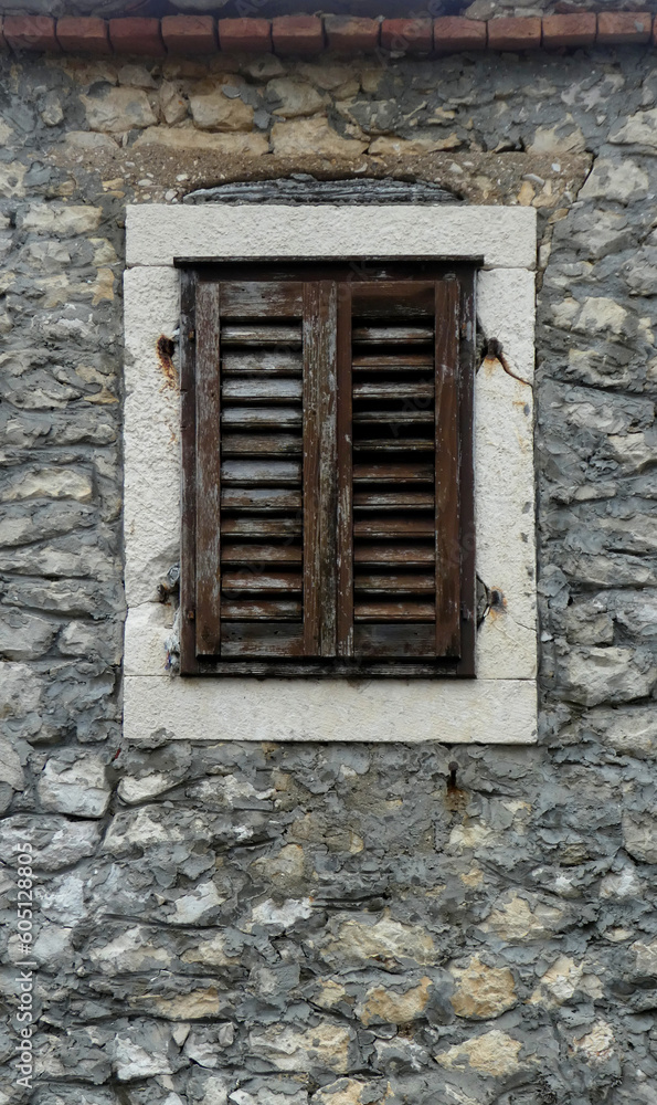 old window with shutters against stone wall on house
