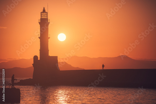 Greece's mesmerizing Chania: A breathtaking sunset and golden hour at the lighthouse in Crete; vibrant hues engulf the sky, illuminating the coastal beauty in a magical Greek setting