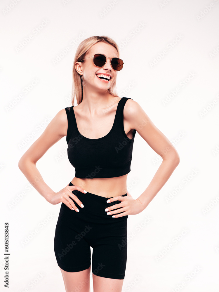 Young beautiful smiling blond female in summer black cycling shorts costume clothes. Sexy carefree woman posing on white in studio. Positive model having fun. Cheerful and happy. In sunglasses Young beautiful smiling blond female in summer black cycling shorts costume clothes. Sexy carefree woman posing on white in studio. Positive model having fun. Cheerful and happy. In sunglasses