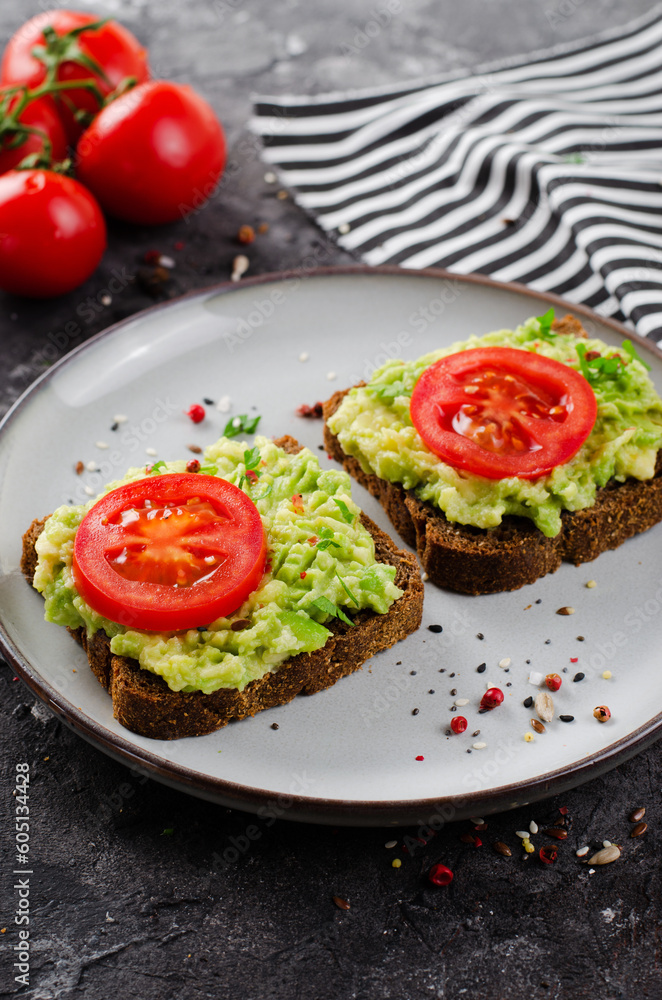Avocado Toasts with Tomato, Healthy Snack or Breakfast on Dark Background Avocado Toasts with Tomato, Healthy Snack or Breakfast on Dark Background