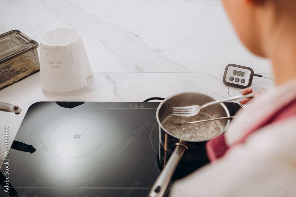 Chef checks the temperature of the heated oil in pot on gas stove with thermometer. Chef checks the temperature of the heated oil in pot on gas stove with thermometer.