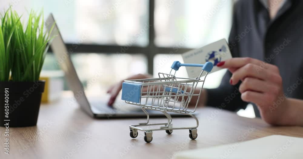 Woman holding plastic credit bank card near toy metal shopping trolley closeup 4k movie. Internet business concept Woman holding plastic credit bank card near toy metal shopping trolley closeup 4k movie. Internet business concept