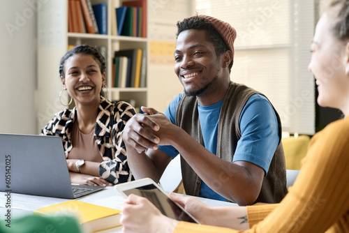 Canvas Print Group of multiethnic students laughing while sitting at table and working in tea