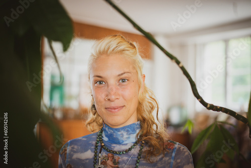 Youthful blonde woman smiles at home in green houseplants photo