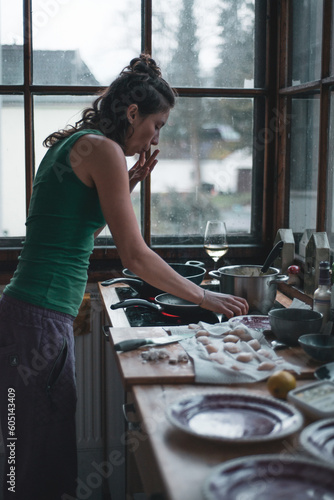 woman tastes food while cooking scallops with wine in kitchen photo