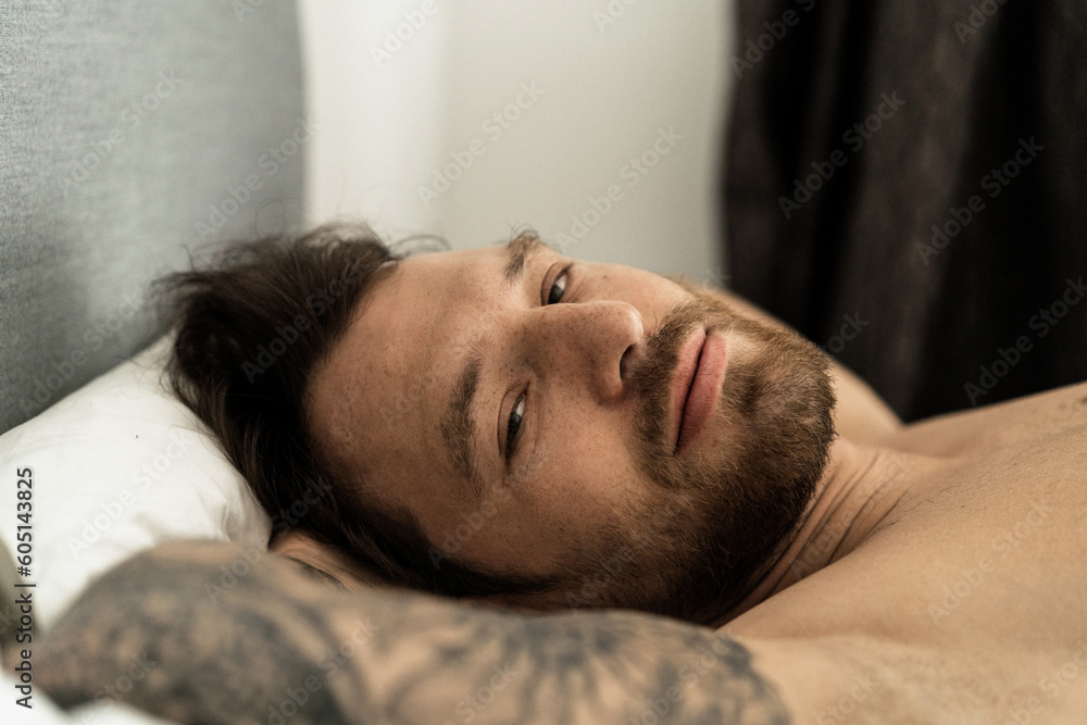 Handsome man in bed after sleep wakes up and starts a new day. Handsome man in bed after sleep wakes up and starts a new day.