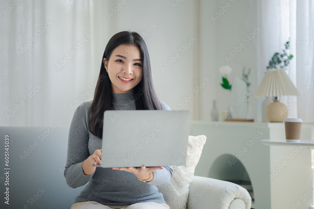 Woman plays on laptop on the sofa in her living room at home, she is resting on weekends after a hard day's work, she relaxes by watching movies and listening to music on her tablet. Holiday concept. Woman plays on laptop on the sofa in her living room at home, she is resting on weekends after a hard day's work, she relaxes by watching movies and listening to music on her tablet. Holiday concept.