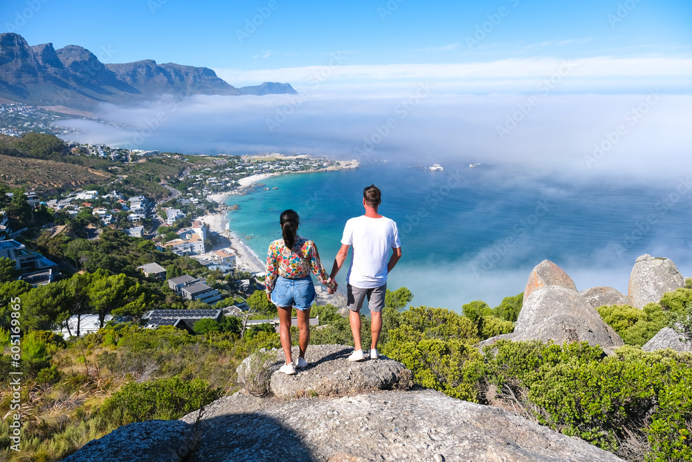 Fototapeta premium a couple of men and women at The Rock viewpoint in Cape Town over Campsbay, view over Camps Bay with fog over the ocean. fog coming in from the ocean at Camps Bay Cape Town South Africa