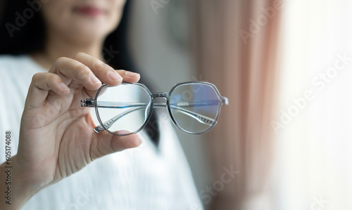 Asian woman in white coat holds glasses in her hands. Vision diagnostics by an optometrist concept.