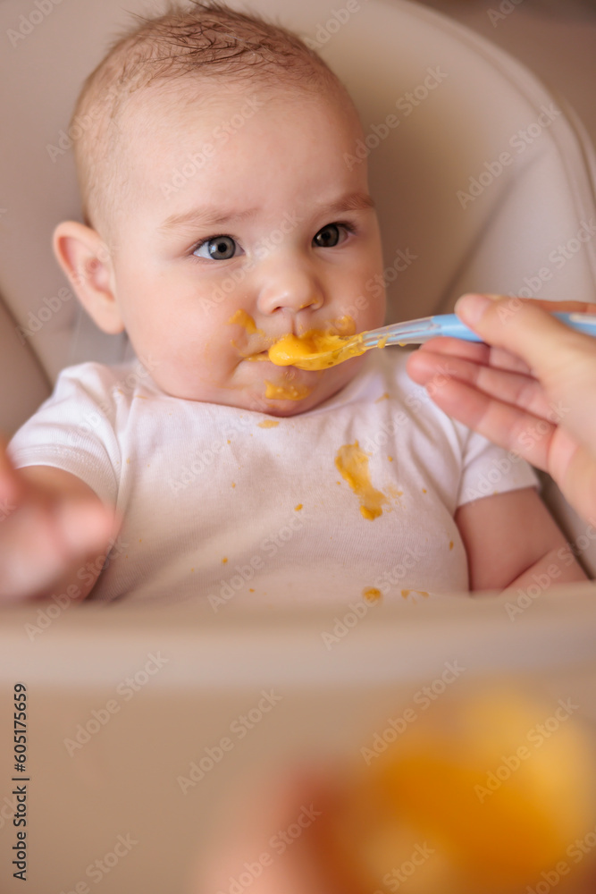 Mother feeding baby boy while introducing solid food Mother feeding baby boy while introducing solid food