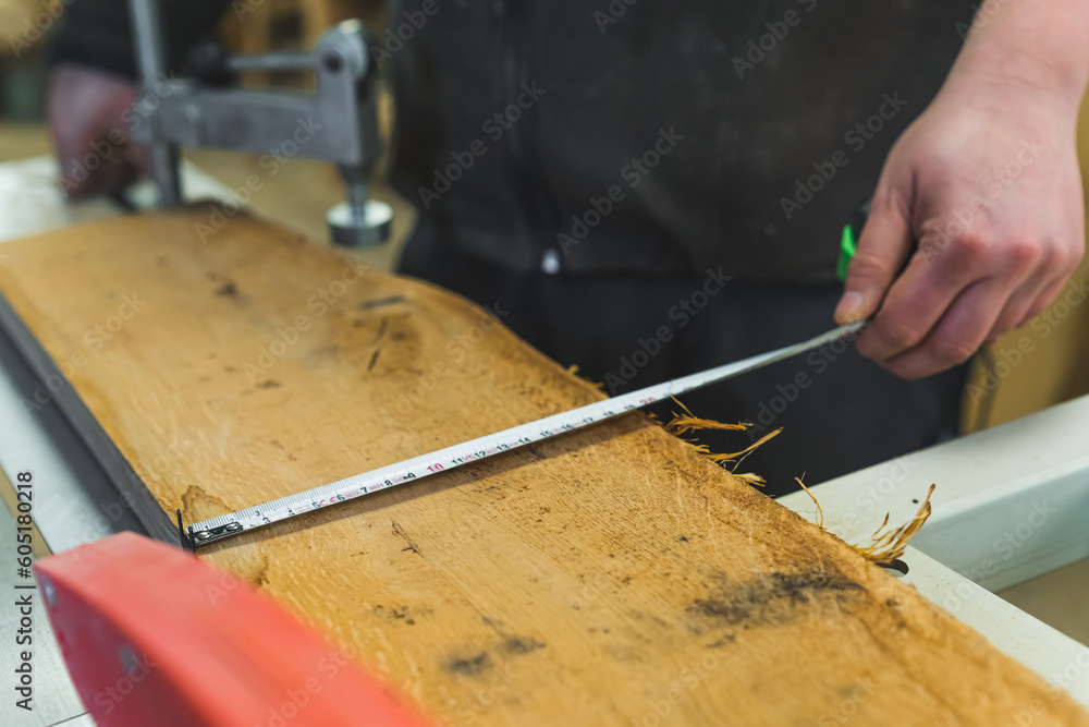 closeup shot of carpenter measuring a wooden piece with a tape measure, working on wood. High quality photo closeup shot of carpenter measuring a wooden piece with a tape measure, working on wood. High quality photo
