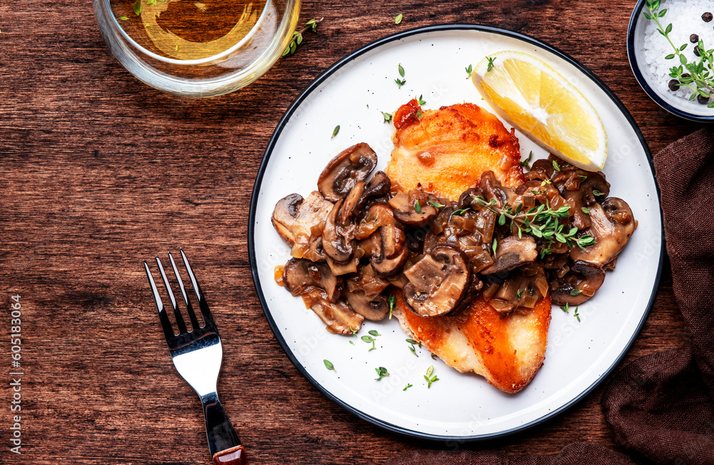 Fried chicken breast with mushrooms and onion sauce with white wine and thyme on plate, old wooden table background, top view Fried chicken breast with mushrooms and onion sauce with white wine and thyme on plate, old wooden table background, top view